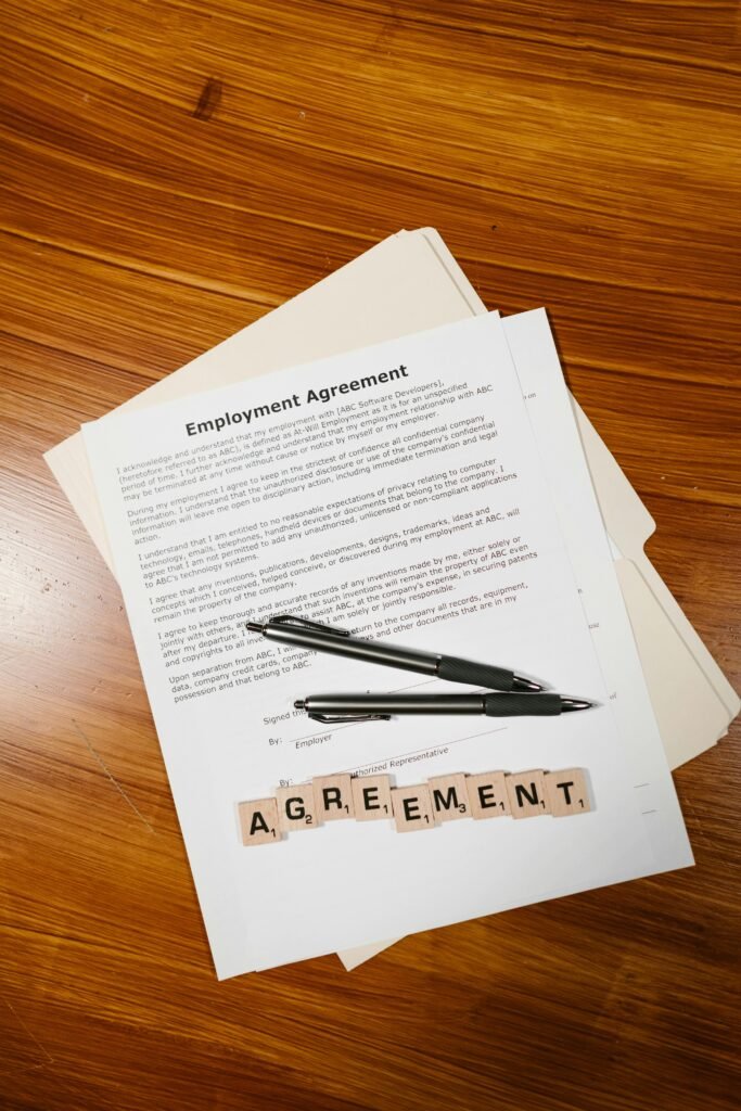 Employment agreement with Scrabble tiles spelling 'AGREEMENT' on wooden surface, captured in detail.